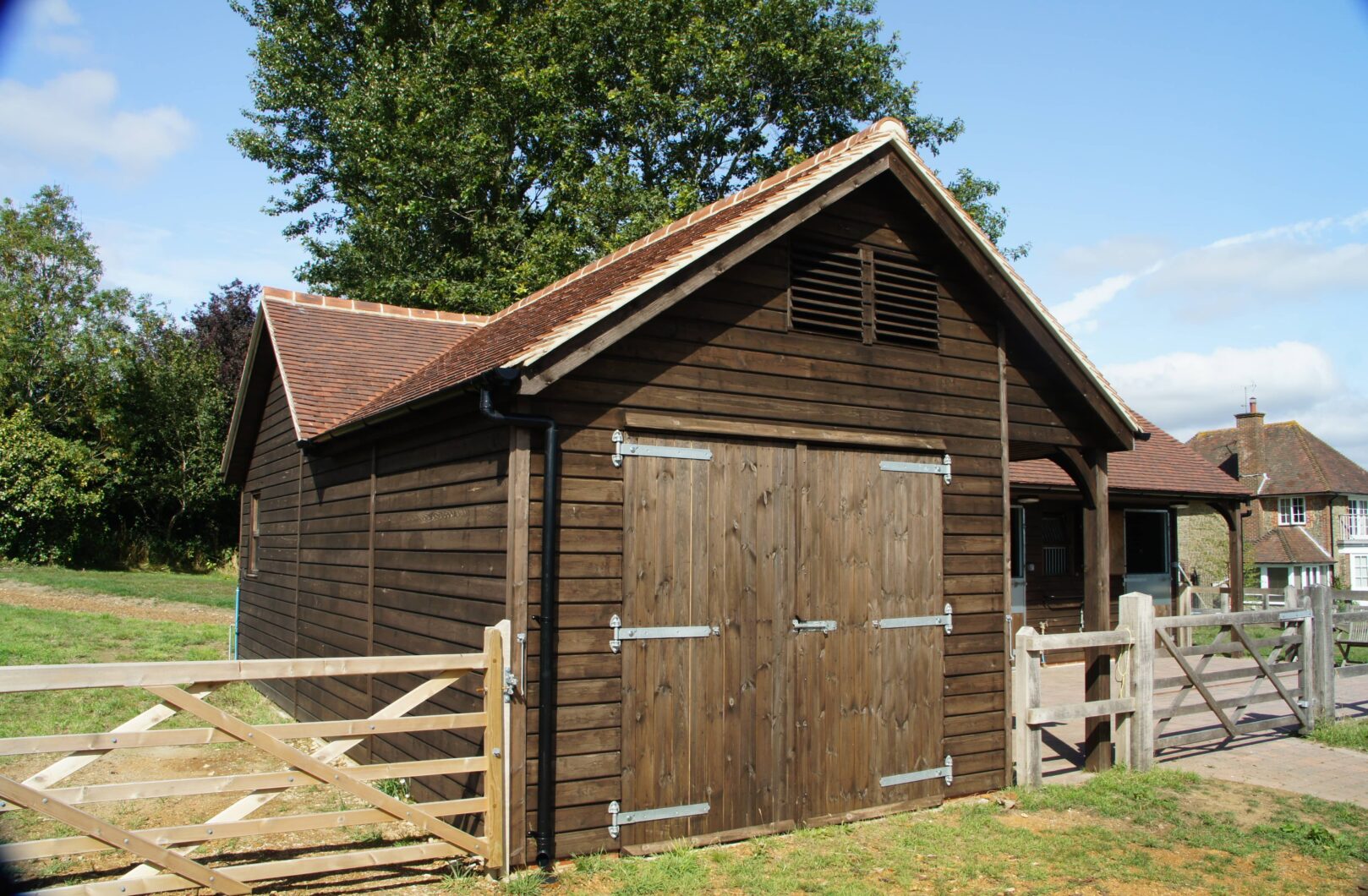 Brown L-shape stable block with clay tiles front barn doors