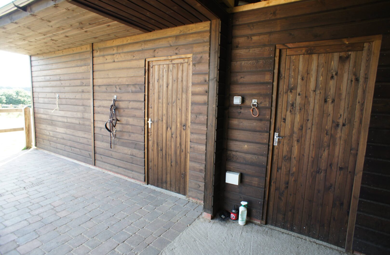 Brown L-shape stable block with clay tiles tack doors closed
