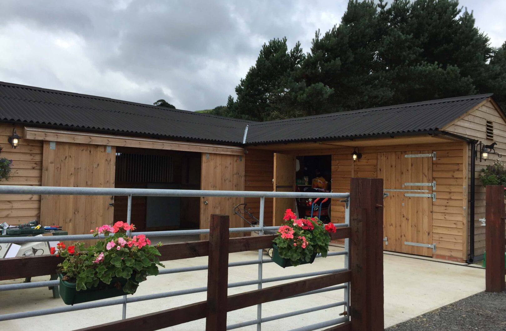American barn with doors open and hanging baskets on the fence in the foreground