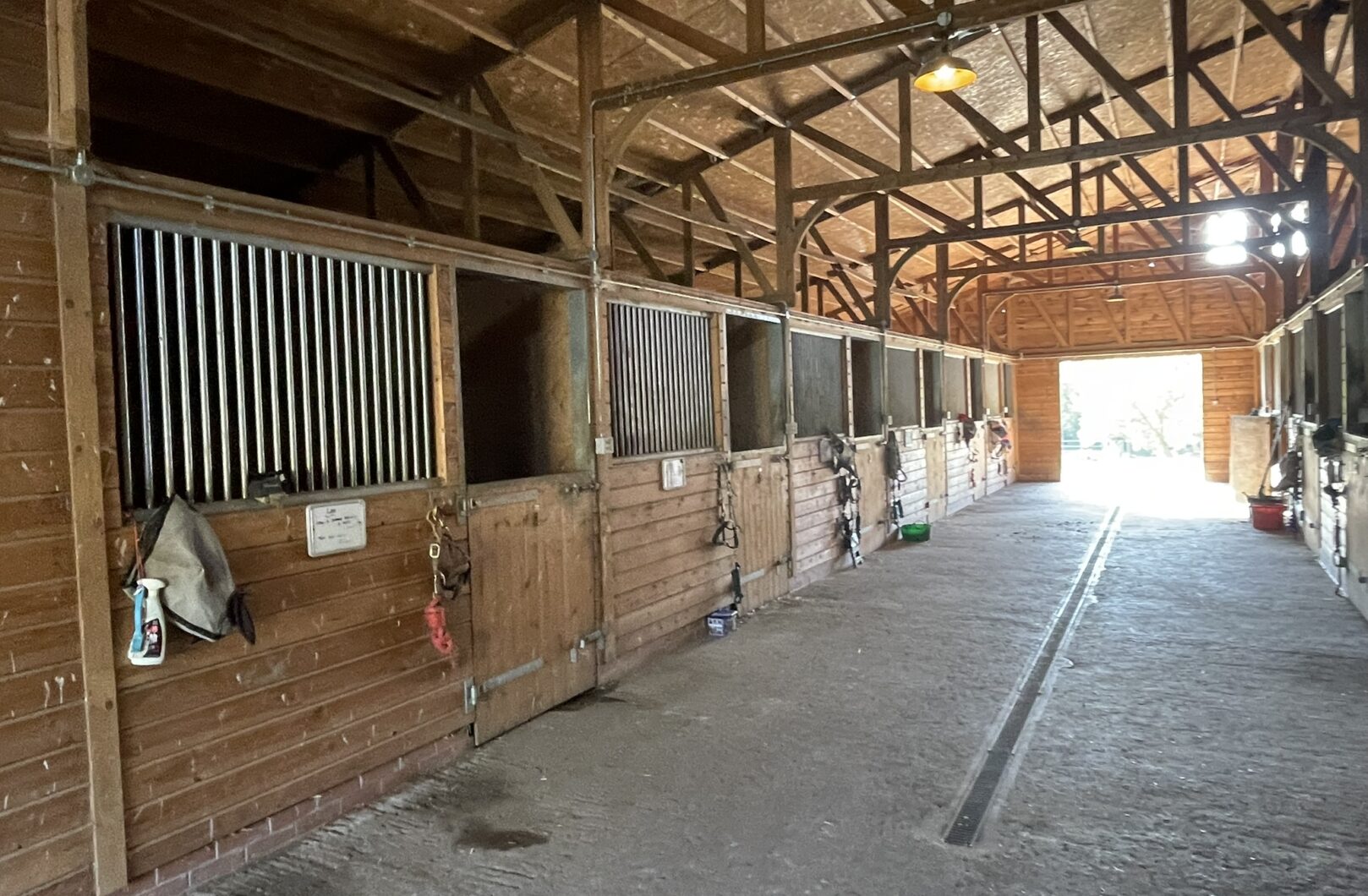 Internal stables showing one side of barn, stable fronts fitted with large talk grills and various pieces of tack