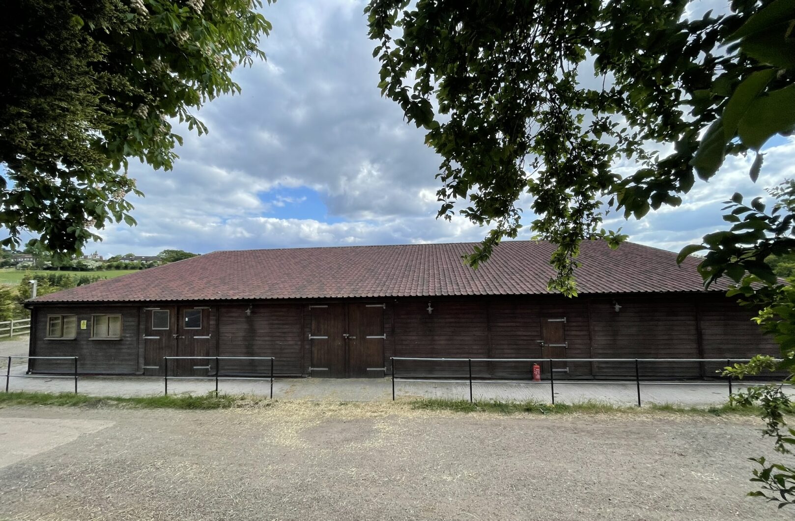 Large american barn with red onduline roof, viewing the long side.