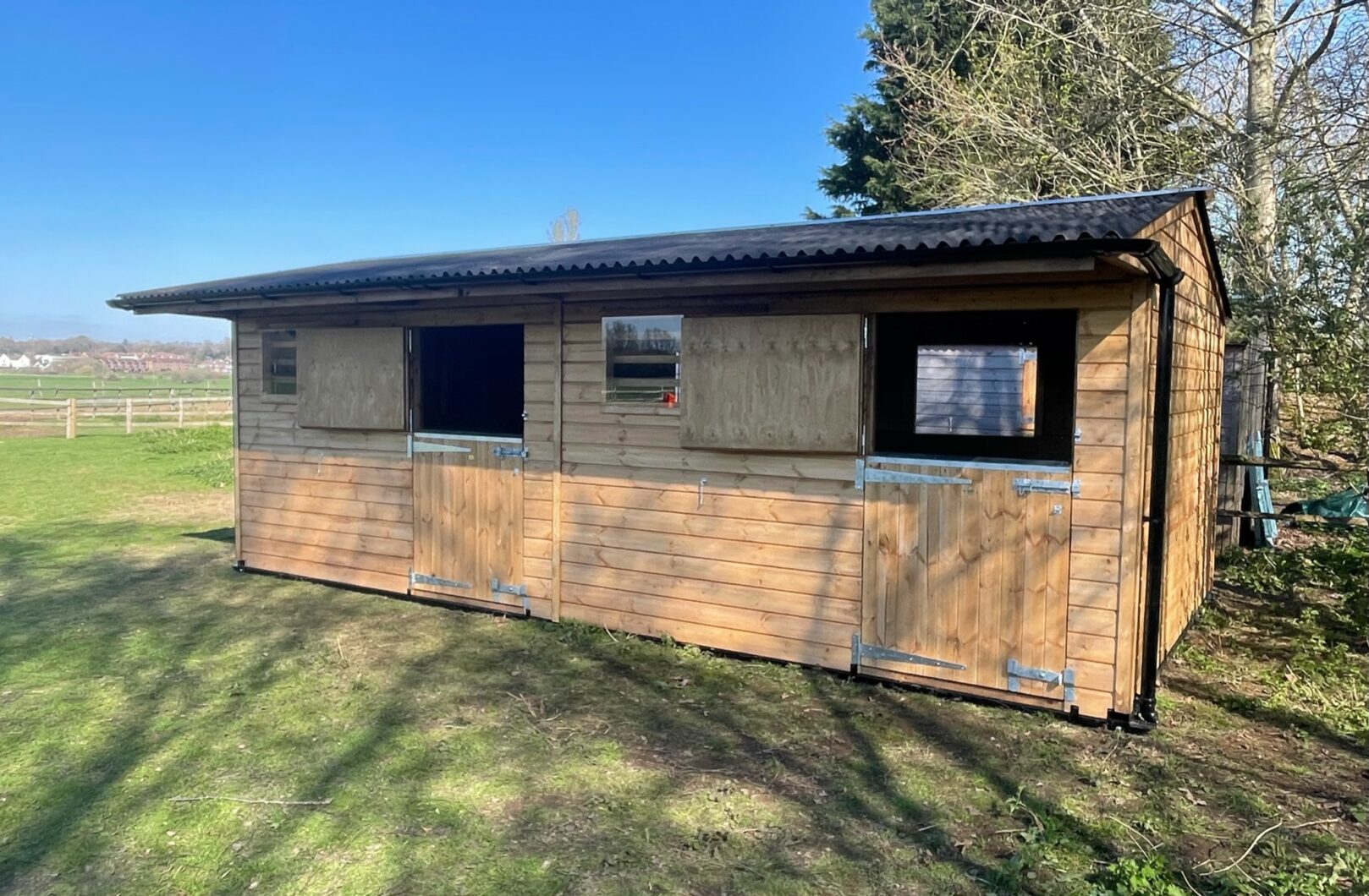 Double mobile stable in a low grass paddock, top stable doors are open