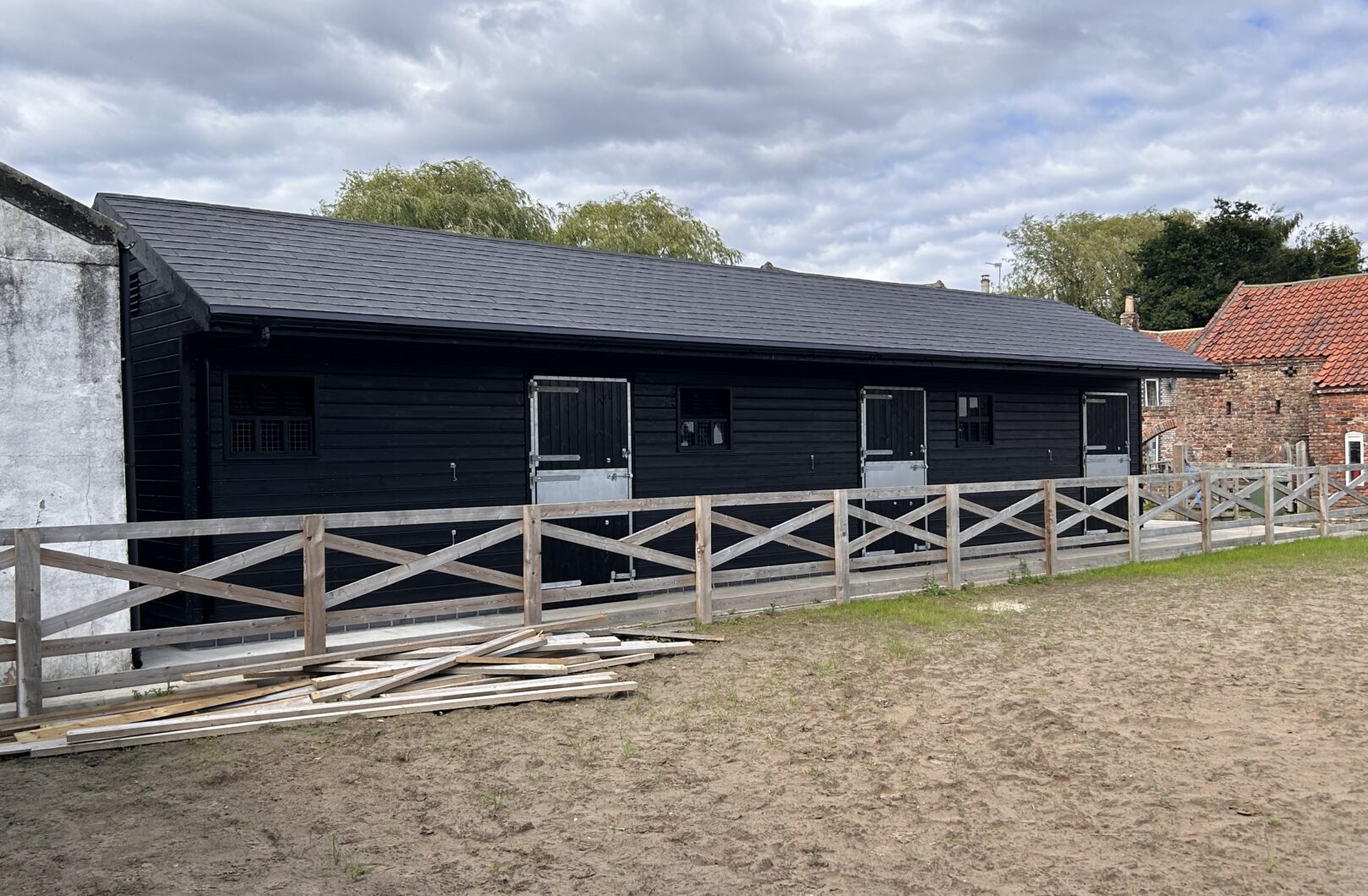 Black stables with fence infront of paddock