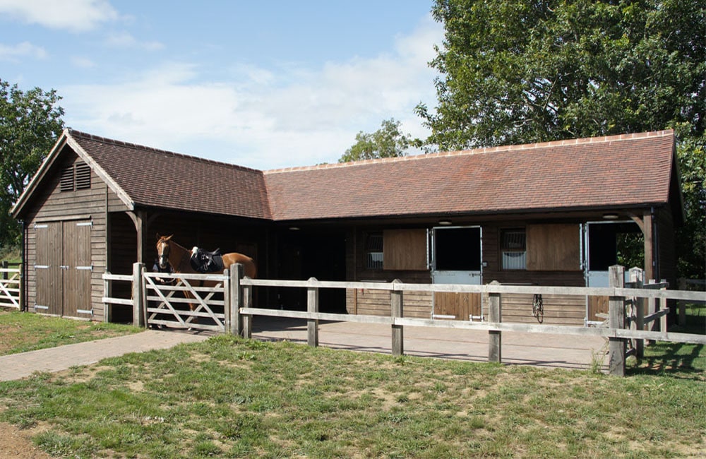 an l-shaped stable block with horses in the stable yard